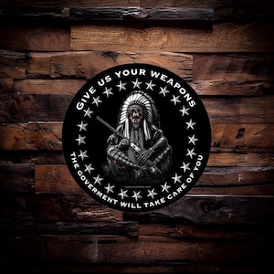 May include: A black and white circular sticker with a Native American warrior holding a rifle. The sticker has the text "Give Us Your Weapons The Government Will Take Care Of You" around the edge.