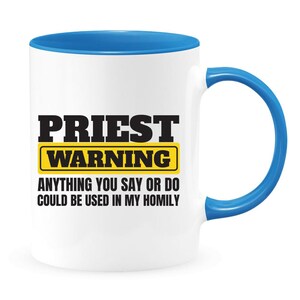 May include: White ceramic mug with a blue rim and handle. The mug has black text that reads "PRIEST WARNING" with a yellow rectangle around the word "WARNING". Below the text is the phrase "ANYTHING YOU SAY OR DO COULD BE USED IN MY HOMILY."