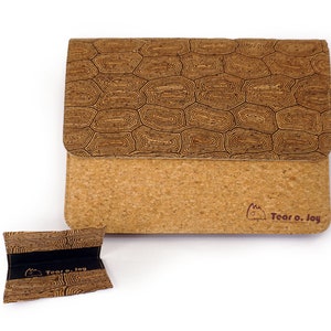 May include: A brown cork wallet with a geometric pattern on the front flap and a small brown cork pouch with the same pattern. The wallet has the text "Tear o. Joy" printed on the bottom right corner.