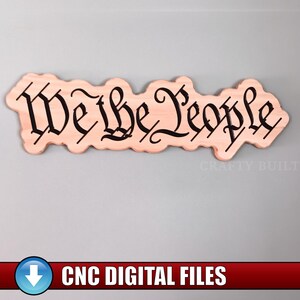 May include: A wooden sign with the phrase "We the People" in black script. The sign has a light brown color and a unique, wavy shape. The words are in a decorative font. The sign is likely a decorative item.