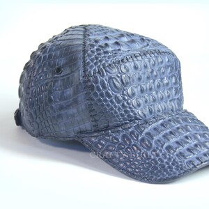 May include: A blue baseball cap made of crocodile leather. The cap has a curved brim and a textured surface.