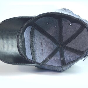 May include: Black leather baseball cap with a gray fleece lining. The inside of the cap has a black mesh panel and the text "CRAFTY BUILT" is visible.