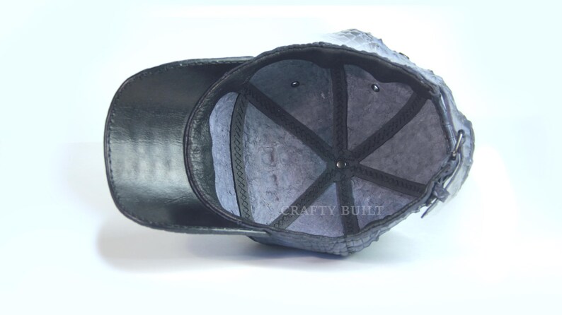 May include: Black leather baseball cap with a gray fleece lining. The inside of the cap has a black mesh panel and the text "CRAFTY BUILT" is visible.