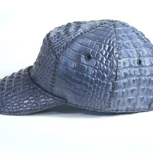 May include: A blue baseball cap made of crocodile leather. The cap has a curved brim and a structured crown.