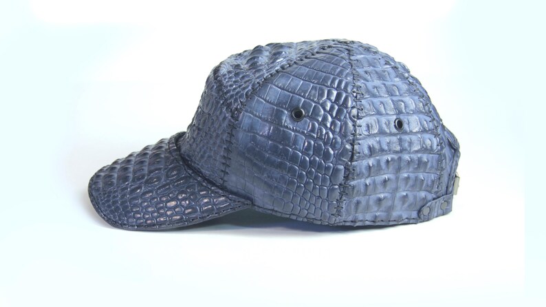 May include: A blue baseball cap made of crocodile leather. The cap has a curved brim and a structured crown.