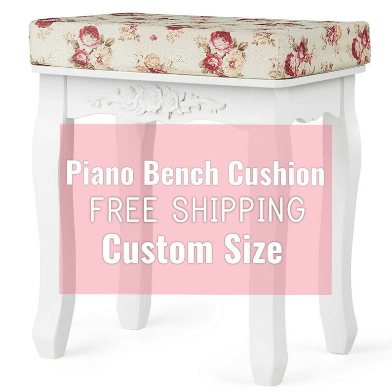 May include: A white wooden piano bench with curved legs and a carved floral detail on the front apron. The top features a rectangular cushion upholstered in a beige fabric with a repeating pattern of red and pink roses and green leaves.
