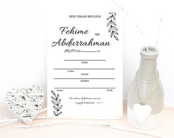 May include: A white wedding certificate with black script, featuring the names "Fehime ve Abdurrahman" and other fields. Decorative floral elements frame the text. A vase with a heart pendant and a woven heart are in the background.