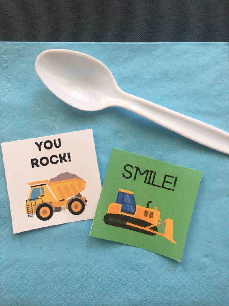May include: Two construction-themed party favor tags. One tag is green with a yellow bulldozer and the text "SMILE!" The other tag is white with a yellow dump truck and the text "YOU ROCK!"
