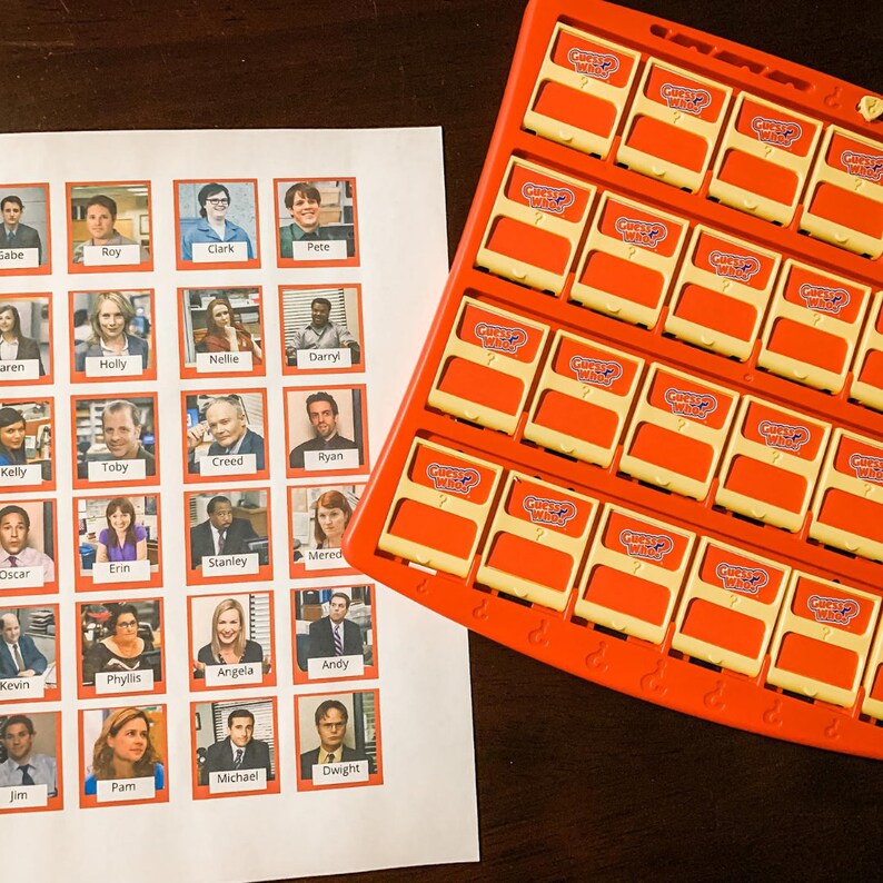Puede incluir: Un juego de Adivina Qui&eacute;n? con personajes del programa de televisi&oacute;n The Office. El tablero de juego tiene un marco rojo y cuadrados amarillos con las palabras "Guess Who?" impresas en ellos. El tablero de juego est&aacute; lleno de peque&ntilde;as im&aacute;genes de pl&aacute;stico de los personajes del programa. El tablero de juego est&aacute; sentado en una mesa de madera.