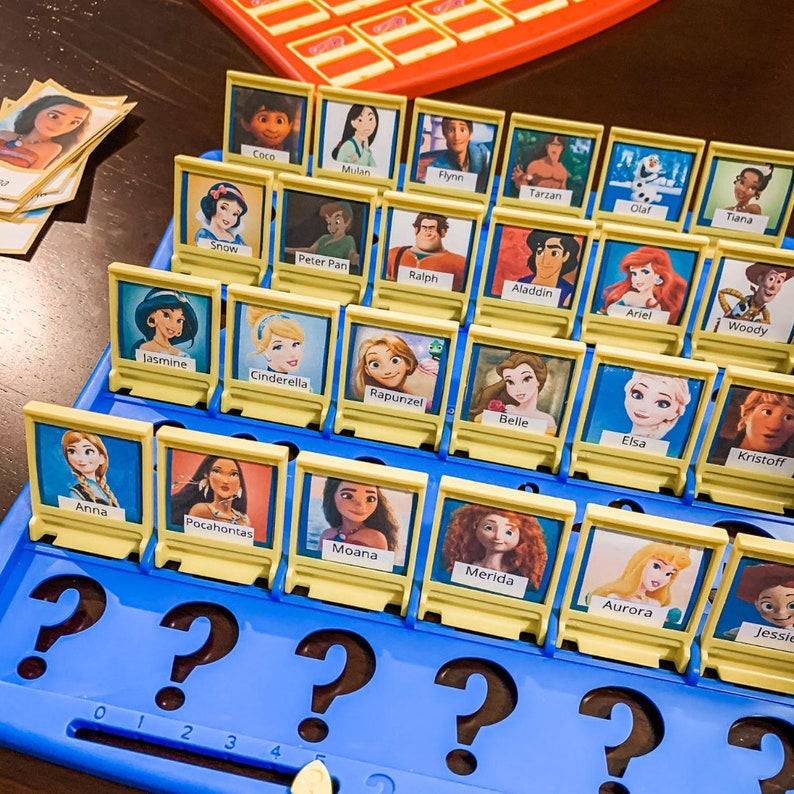 Puede incluir: Un tablero de juego amarillo y azul con una cuadr&iacute;cula de 30 casillas. Cada casilla tiene una imagen de un personaje de Disney, como Blancanieves, Aladdin y Elsa. El tablero de juego est&aacute; etiquetado con los n&uacute;meros del 1 al 5.