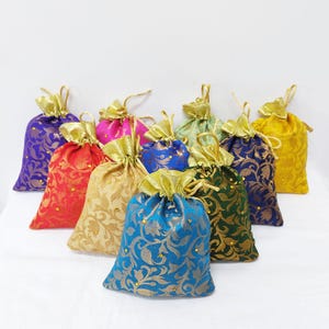 May include: Assortment of colourful fabric drawstring pouches with gold accents and floral patterns. The pouches are made of brocade fabric and have a satin ribbon tie.