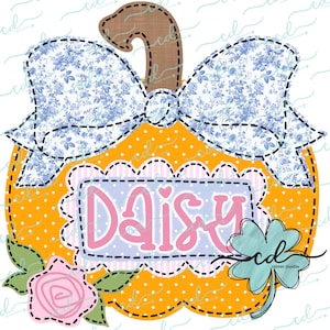 Pode incluir: Uma abóbora amarela com um laço floral azul e branco, uma etiqueta de nome rosa e roxa que diz "Daisy" e um trevo de quatro folhas verde.