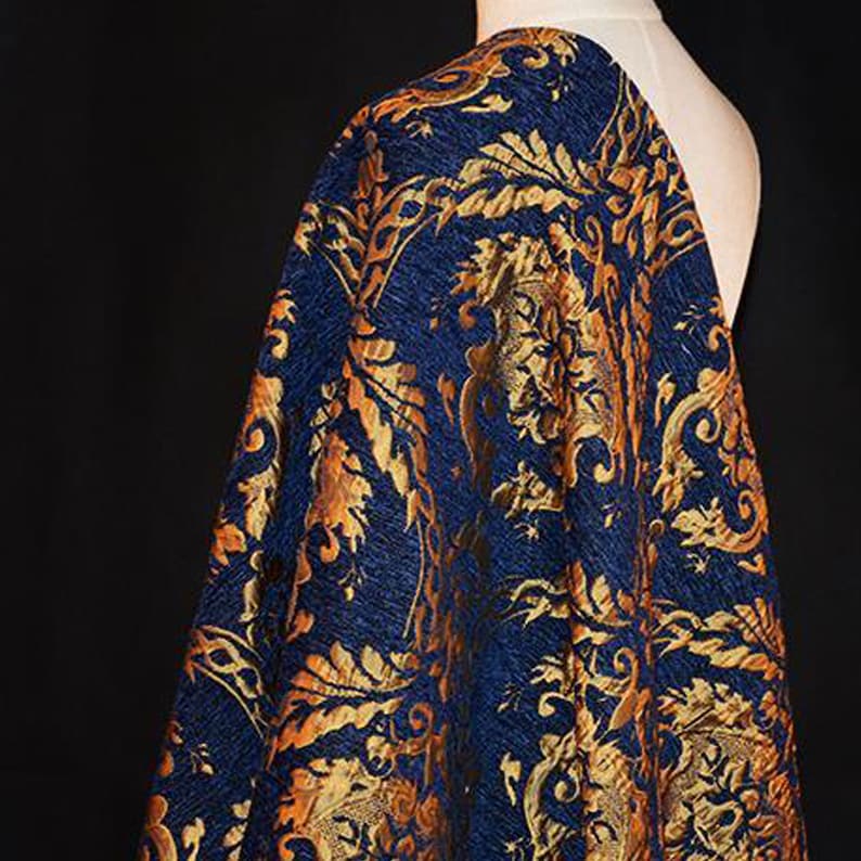 May include: Blue fabric with a gold and orange floral pattern. The fabric has a textured, brocade-like appearance.