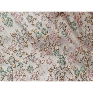 May include: White fabric with a raised floral pattern in shades of pink, green, and gold.