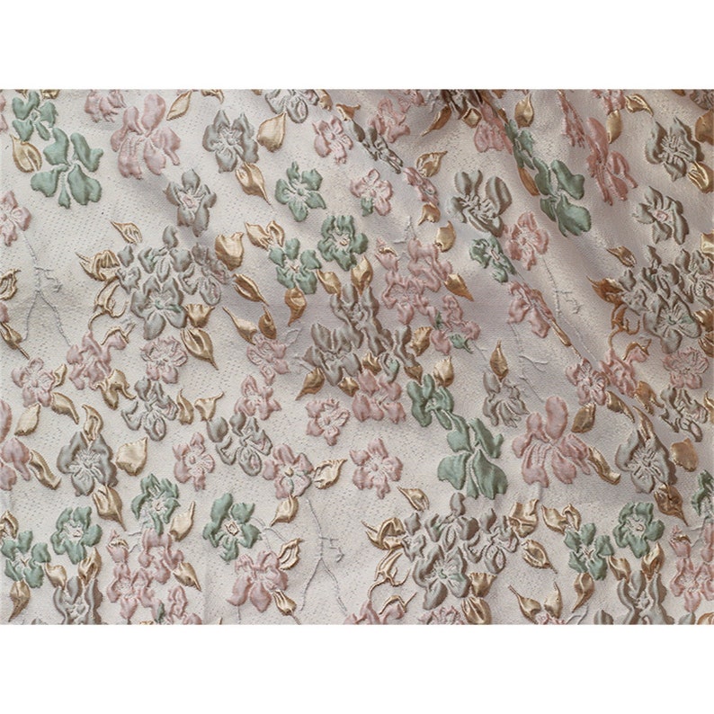 May include: White fabric with a raised floral pattern in shades of pink, green, and gold.