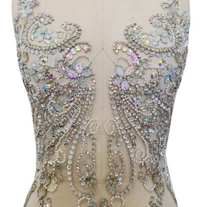 May include: A large, ornate, silver-toned, beaded applique with iridescent crystals and pearls. The applique is designed in a floral pattern with a central butterfly motif.