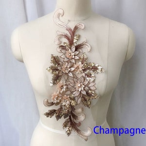 May include: A delicate floral applique with gold sequins and beige embroidery. The applique features a cluster of flowers with a champagne colour.