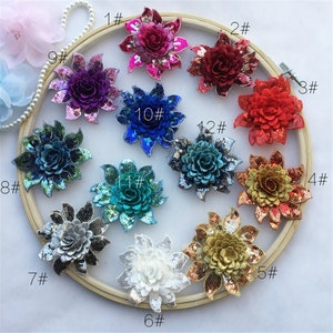 May include: Twelve different sequin flower embellishments in various colours, including red, blue, green, gold, silver, and white. Each flower is numbered 1 through 12.