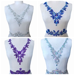 May include: Four different rhinestone embellishments for clothing. The embellishments are in the shapes of a V-neckline and a waist band. The embellishments are in silver, blue, purple, and iridescent.