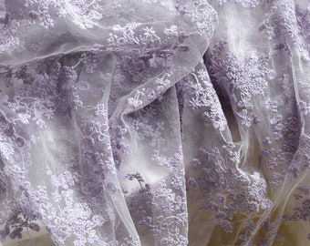 May include: Purple embroidered lace fabric with a delicate floral pattern. The lace is sheer and lightweight, making it perfect for a variety of crafting projects.