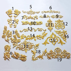 May include: Nineteen gold embroidered patches with various floral and scroll designs. The patches are numbered 1 through 19.