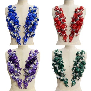 Può includere: Quattro paia di applicazioni di fiori in tessuto, ogni coppia è di un colore diverso. Le applicazioni sono realizzate in tessuto satinato e hanno un effetto 3D. I colori sono blu, rosso, viola e verde.