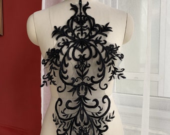 May include: Black lace applique with a floral and scroll design. The applique is about 18 inches tall and 10 inches wide.