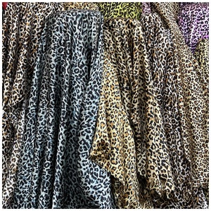 May include: A selection of leopard print fabrics in various colours, including black, brown, and blue. The fabrics are draped over a surface and arranged in a vertical pattern.