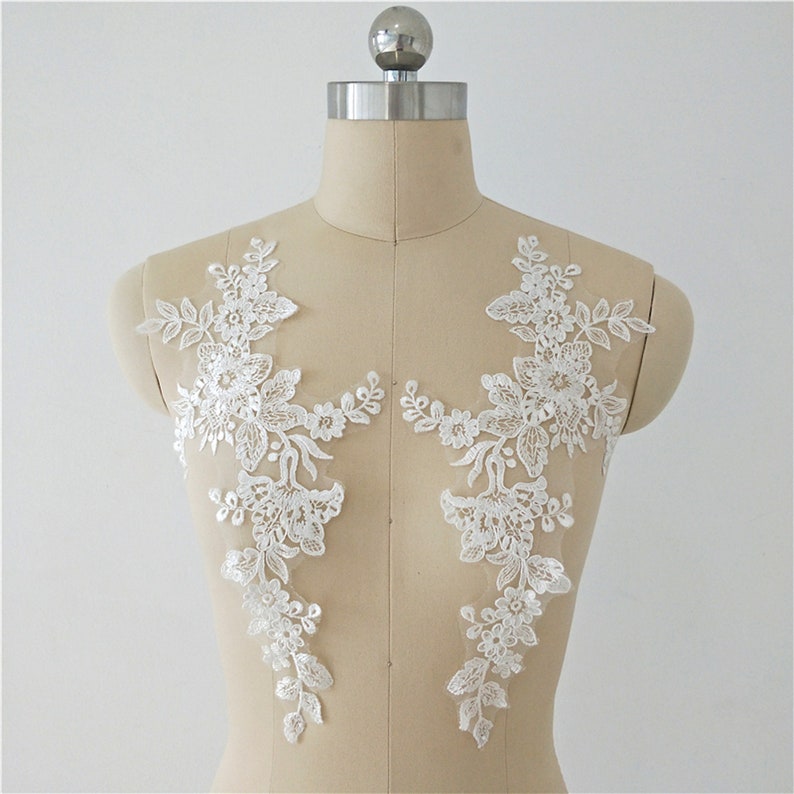 May include: Two white floral lace appliques, perfect for adding a touch of elegance to wedding dresses, bridal accessories, or other craft projects.