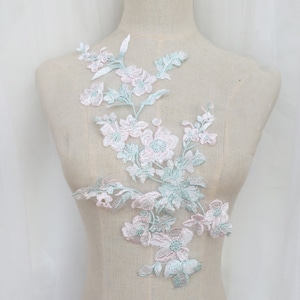 May include: A delicate floral lace applique with pink and light blue flowers and leaves. This applique is perfect for adding a touch of elegance to clothing, accessories, or home decor projects.