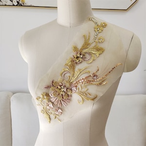 May include: Gold and pink floral applique with sequins and rhinestones on a sheer mesh fabric. This applique is perfect for adding a touch of elegance to any garment or project.