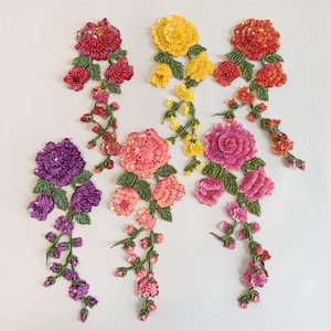 Pode incluir: Apliques florais bordados em várias cores, incluindo vermelho, amarelo, laranja, rosa e roxo. Cada aplique apresenta detalhes de lantejoulas e contas, com folhas e caules verdes. Estes apliques decorativos são ideais para embelezar roupas ou acessórios.
