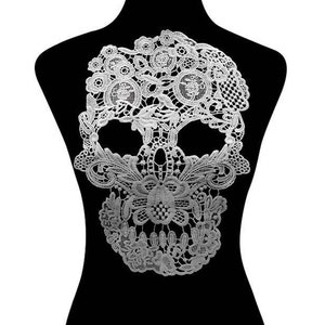May include: White lace skull applique. The skull is made of delicate lace with intricate floral designs. This applique is perfect for adding a touch of gothic elegance to any project.