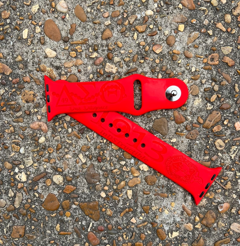May include: Red Apple Watch band with a Greek letter design and the words "Due Diligence" and "1913 Indstructible".