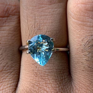 Könnte beinhalten: Ein silberner Ring mit einem hellblauen Aquamarin-Edelstein in Herzform.