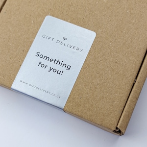 May include: A brown cardboard box with a silver label that reads "GIFT DELIVERY" and "Something for you!" The website address www.giftdelivery.co.uk is also visible. The box is partially open.