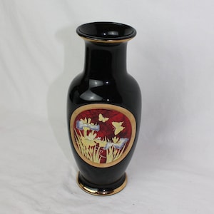 Puede incluir: Jarrón de cerámica negro con borde dorado y un diseño floral rojo, dorado y blanco con mariposas.