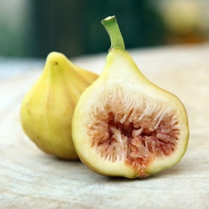 May include: Two ripe figs, one cut open to reveal its red interior. The figs are pale yellow with a slightly green stem.