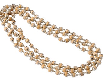 May include: A triple-strand necklace featuring light brown wooden beads with silver-colored metal accents. The beads are evenly spaced and strung together, creating a layered effect. The necklace is displayed against a white background.
