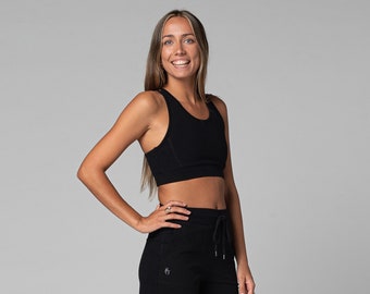 Könnte beinhalten: Schwarzer Sport-BH und passende schwarze Sporthose. Der BH hat einen Rundhalsausschnitt und ein Racerback-Design. Die Shorts haben einen Kordelzug in der Taille und Taschen. Das Outfit besteht aus einem weichen, dehnbaren Material, ideal für Workouts.