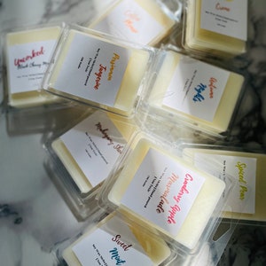 May include: Assortment of soy wax melts in clear plastic containers. The scents include Spiced Pear, Cranberry Apple Marmalade, Mahogany Shea, Persimmon Tangerine, Sweet Mint, and Uncorked Black Cherry Merlot. Each container has a label with the scent name and the text "Soy Wax Melts Hand Poured, Non Toxic".