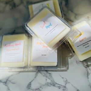 May include: A collection of six soy wax melts in clear plastic containers. The wax melts are hand-poured and non-toxic. The scents include Cranberry Apple Marmalade, Sweet Mint, Pear Jam, Lemonade Creme.