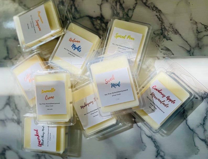 May include: Assortment of soy wax melts in clear plastic packaging. The wax melts are labeled with various scents, including Cranberry Apple Marmalade, Sweet Mint, Limoncello Creme, Spiced Pear, Autumn Nights, and Uncorked Black Cherry Almond.