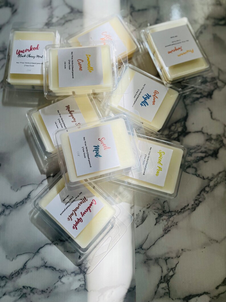 May include: A collection of wax melts in clear plastic containers with labels. The labels have different scents, including Cranberry Apple, Mahogany & Spice, Sweet Mint, Spiced Pear, Limoncello Creme, Autumn Nights, and Tangerine.