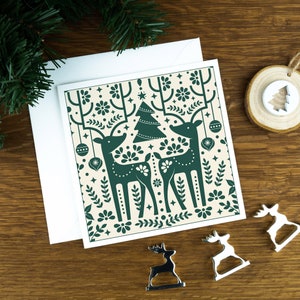 Luxus Skandinavische Weihnachtskarte für Familie, Weihnachten 2024, grüne Rentiere auf hellem Hintergrund.