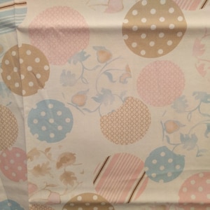 May include: White fabric with a repeating pattern of pastel pink, blue, and brown circles with different designs. Some circles have polka dots, others have stripes, and others have a geometric pattern.