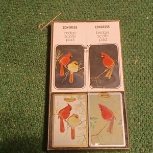 May include: A set of four bridge score pads with a red cardinal bird illustration on each card. The cards are labeled "Congress Bridge Score Pad".