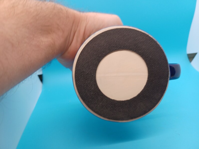 Pu&ograve; includere: Il fondo di una tazza in ceramica blu con un anello di gomma nero attorno alla base. La tazza ha un cerchio bianco al centro dell'anello di gomma.