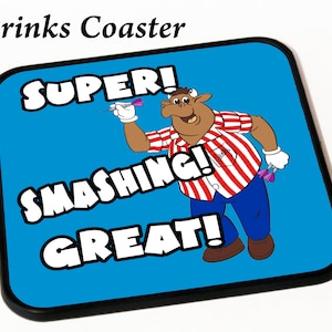 May include: A blue drinks coaster featuring a cartoon illustration of a person throwing darts. The text on the coaster reads "SUPER! SMASHING! GREAT!"