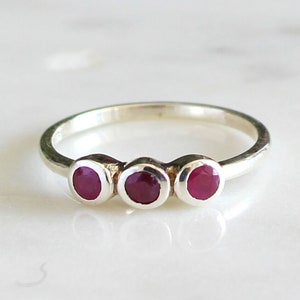 Peut inclure: Une bague en argent avec trois pierres rondes rouges.